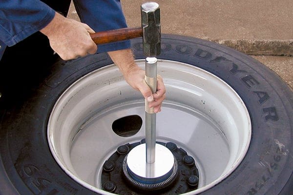 Someone using a mallet on a lug nut.